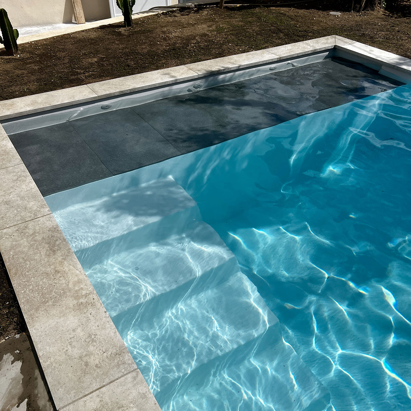 Vue détaillée de l'angle de la piscine Divine 80 mettant en avant les finitions grès cérame.