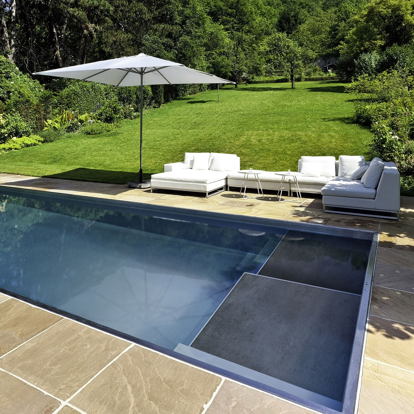 Vue d'ensemble de la piscine coque XL Étonnante 85 installée avec sa plage immergée.