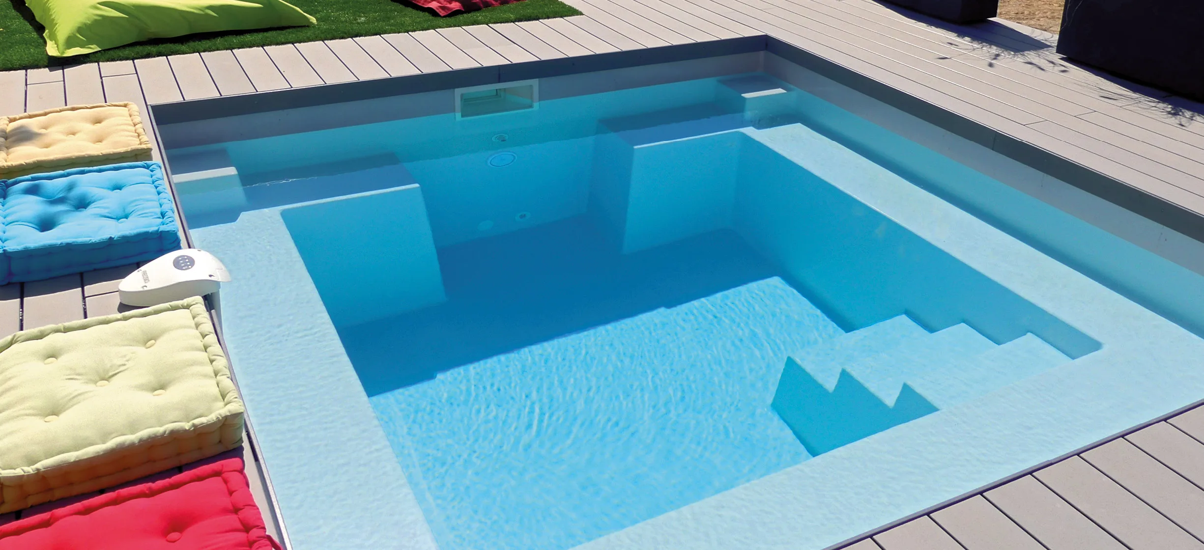 Petite piscine coque Mini-Carré installée dans un jardin avec pelouse.