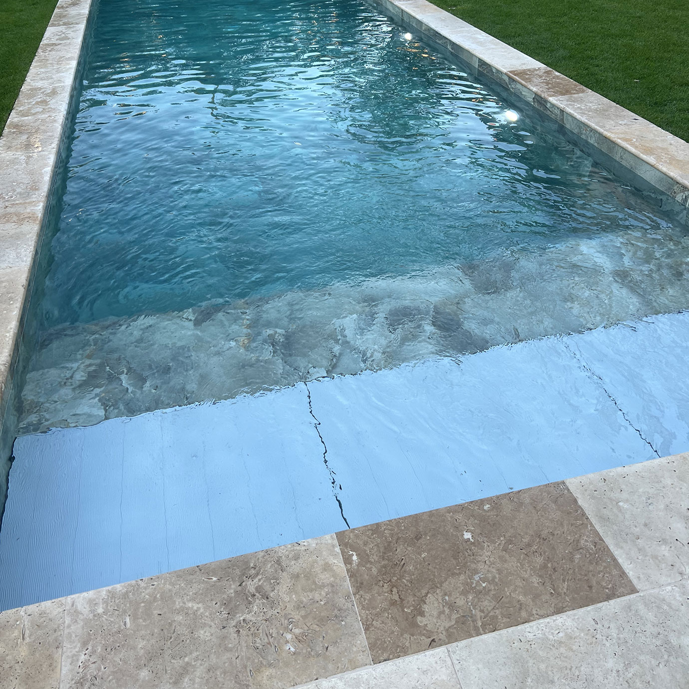 Détail de la pose des margelles en grès cérame sur une piscine coque Divine 100.