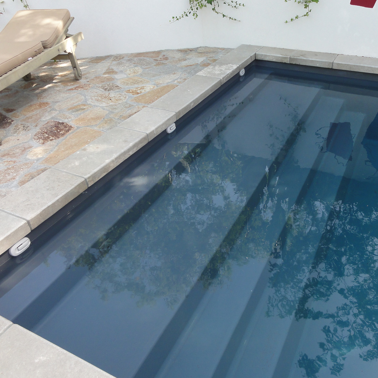 Zoom sur l'escalier d'angle et la banquette de repos de la piscine coque Podestat.