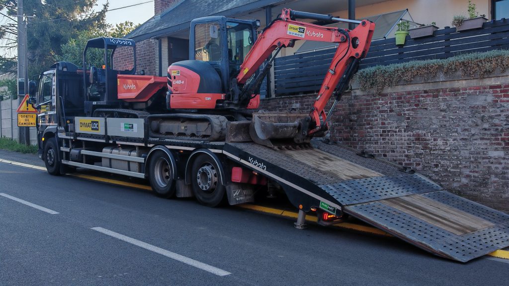 Camion porte-engin de la société OVMAT LOC arrivant à Caudry avec les machines de terrassement pour la piscine.