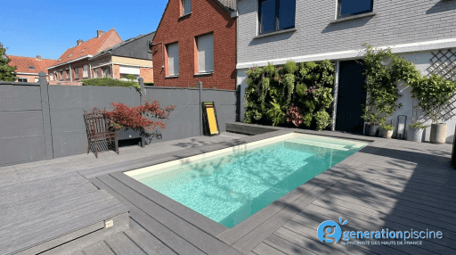 Vue d'ensemble d'une mini piscine coque blanche installée dans une terrasse composite grise avec mur végétal à Marcq-en-Barœul.