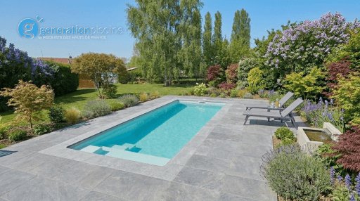 Vue finale d'une piscine Mini Couloir à Caudry avec des margelles grises, une terrasse en pierre et un jardin paysager arboré de lilas et de maples.